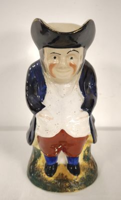 une figurine en céramique représentant un homme portant un chapeau et un pantalon rouge