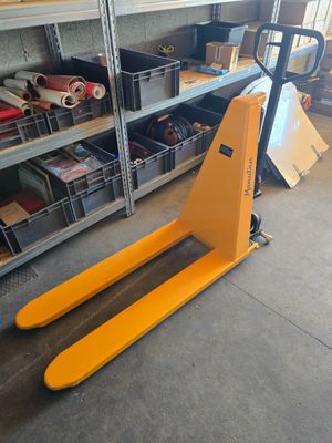 un chariot élévateur dans un entrepôt où se trouvent de nombreux cartons au sol