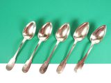 six spoons are lined up on a green surface
