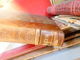 un livre marron posé au sommet d'une pile de livres