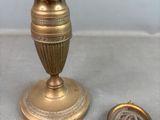 un petit vase en or posé à côté d'une pièce de monnaie sur une table