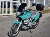 a blue motorcycle parked in front of a white fence