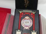 une boîte rouge avec un couvercle noir et l'image d'un livre à l'intérieur