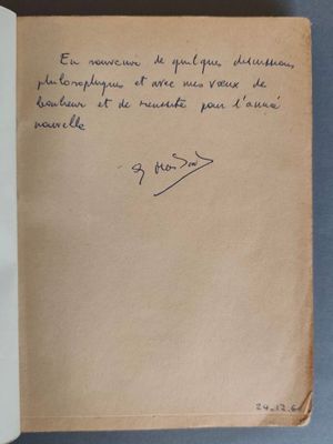 un livre ouvert, sur lequel est posée une note manuscrite, posé sur une table