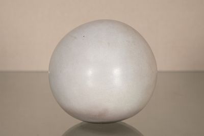 un œuf blanc posé sur une table, avec un mur blanc en arrière-plan