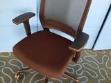 une photo d'une chaise de bureau marron posée sur un tapis dans une pièce