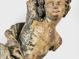 an old statue of a child laying on its back on a white surface
