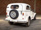 a small white car that is parked in front of a brick wall