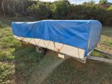 a blue and white boat on a trailer in the grass
