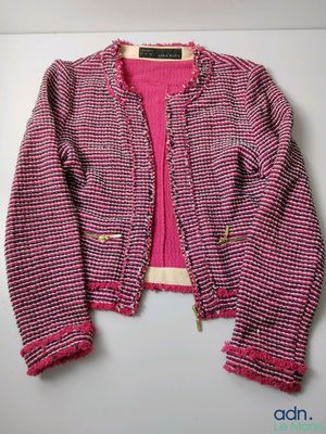 a close up of a pink sweater and jacket hanging on a wall