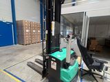 Le chariot élévateur est garé dans l'entrepôt, avec des cartons en arrière-plan.