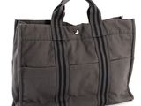 grey canvas tote bag with black zippers on a white background