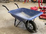 une brouette bleue dans un garage, avec des outils par terre