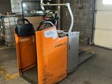 a forklift in a warehouse with a cart in the background