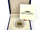 une pièce d'or dans une boîte bleue avec une boîte blanche