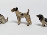 three small figurines of dogs on a white surface