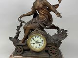 a bronze statue of a woman sitting on a carriage with a clock