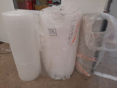 two rolls of plastic wrap on the floor next to a roll of plastic