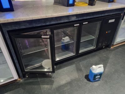 un petit réfrigérateur avec deux bouteilles d'eau posées sur le plan de travail