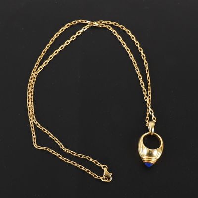 un collier en or avec une pierre bleue suspendue à une chaîne