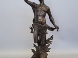 statue en bronze représentant un garçon tenant une fleur, posée sur un socle en bois