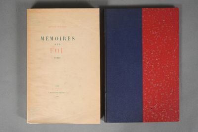 an old book sitting on top of a table next to a red and blue book