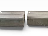 deux boîtes métalliques munies de poignées, posées sur une surface blanche