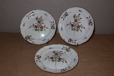 trois assiettes ornées de fleurs posées sur une table
