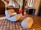une chaise blanche et un pouf dans une pièce au sol à carreaux