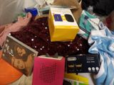 a pile of items on a bed that includes a radio, a cell phone, a book, and other items