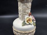 a white vase with a flower on top of it