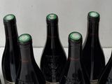 six bottles of wine are lined up in a row on a counter