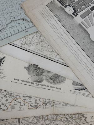 de nombreuses vieilles cartes posées sur une table, avec des ciseaux et une paire de ciseaux