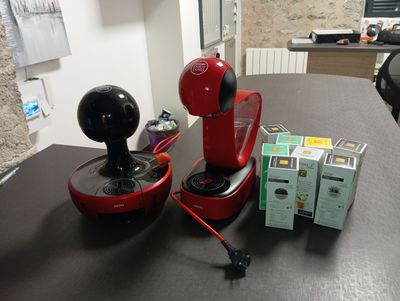 une cafetière rouge posée sur une table, à côté d'une boîte de thé