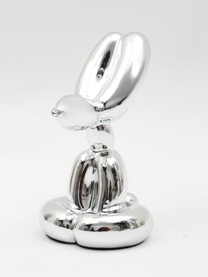 a silver sculpture of a bird sitting on top of a plate