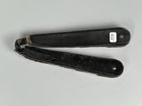 pair of black folding pocket knives sitting on top of a white table