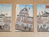 trois tableaux accrochés au mur d'un immeuble doté d'une tour horloge