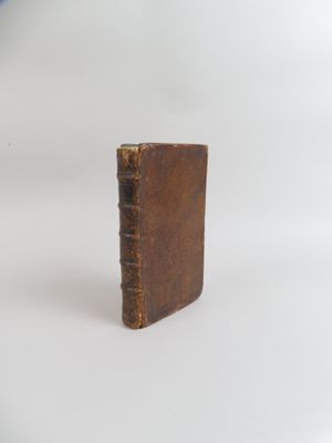 un petit livre marron posé sur une surface blanche