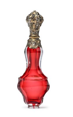 une image représentant un flacon de parfum en verre rouge muni d'un bouchon doré