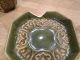 a green bowl with a decorative design on it on a table
