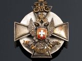 a silver and gold medal with a red cross on it
