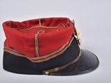 red and black military hat with gold buckles on top of it