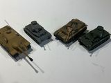 four small toy tanks on a white surface