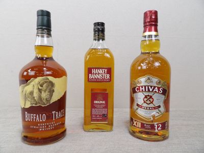 trois bouteilles d'alcools de différentes sortes posées les unes à côté des autres