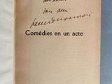un livre ouvert, sur lequel est inscrit un poème manuscrit, posé sur une table