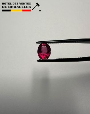 a close up of a pair of pliers holding a pink diamond