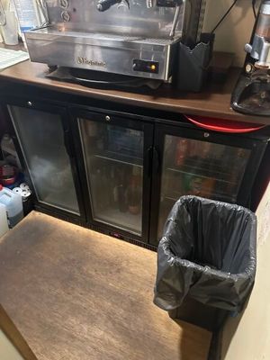une machine à café posée sur un plan de travail, à côté d'une poubelle