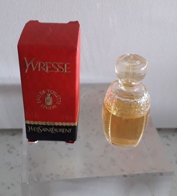 un petit flacon de parfum à côté d'une boîte rouge