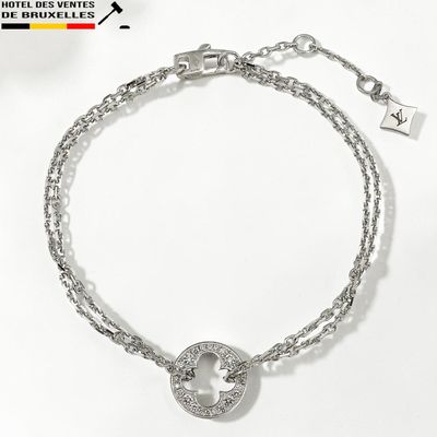 Le bracelet est en métal argenté et présente un motif circulaire.