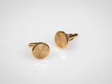 une paire de boutons de manchette en or sur fond blanc